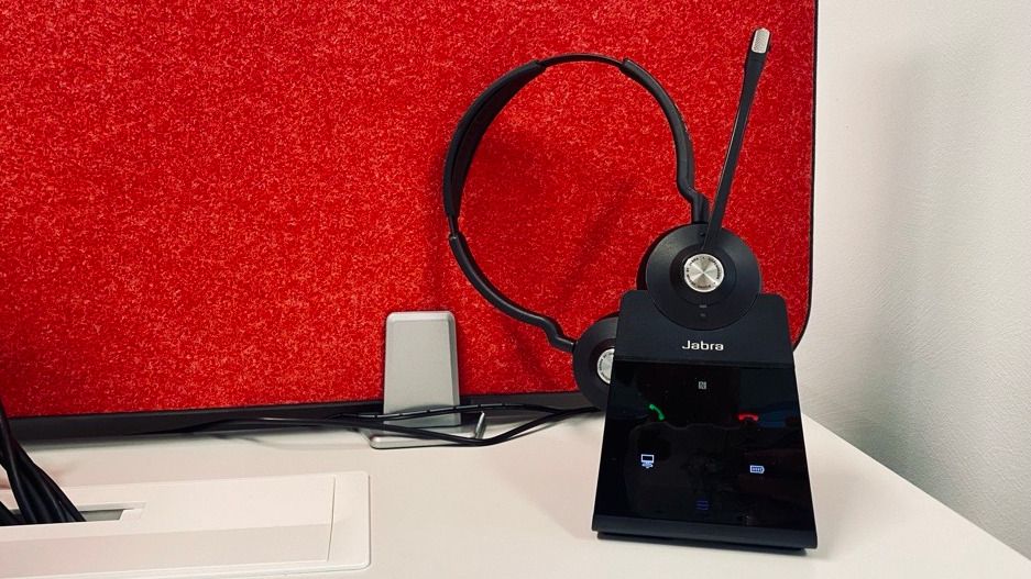 Ein Headset in seiner Ladestation vor einer roten schallabsorbierenden Wand.