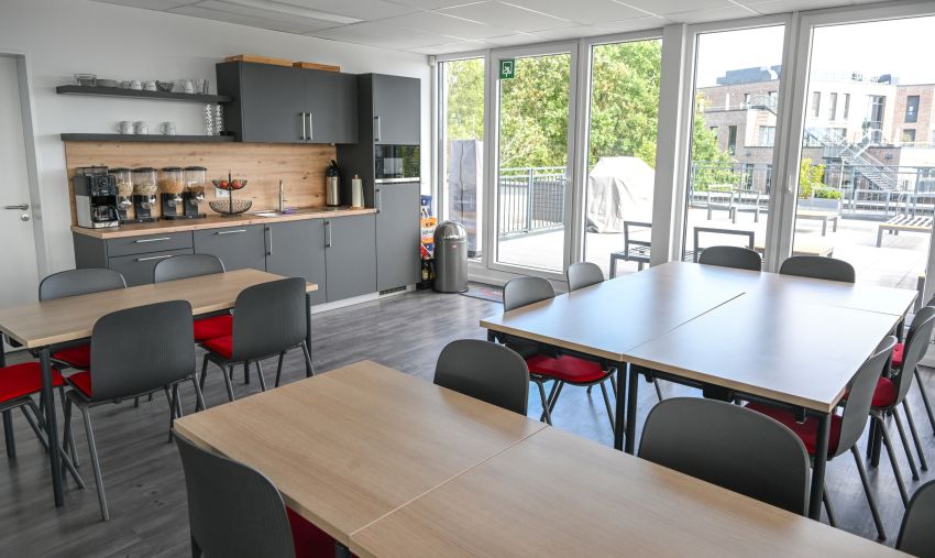 Foto des Pausenraums mit Zugang zur Dachterrasse und einer offenen Küche.