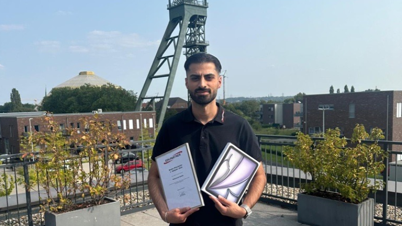 Mitarbeiter des Halbjahres Mohammed Saleha hält ein Tablet und seine Auszeichnung als Mitarbeiter des Halbjahres